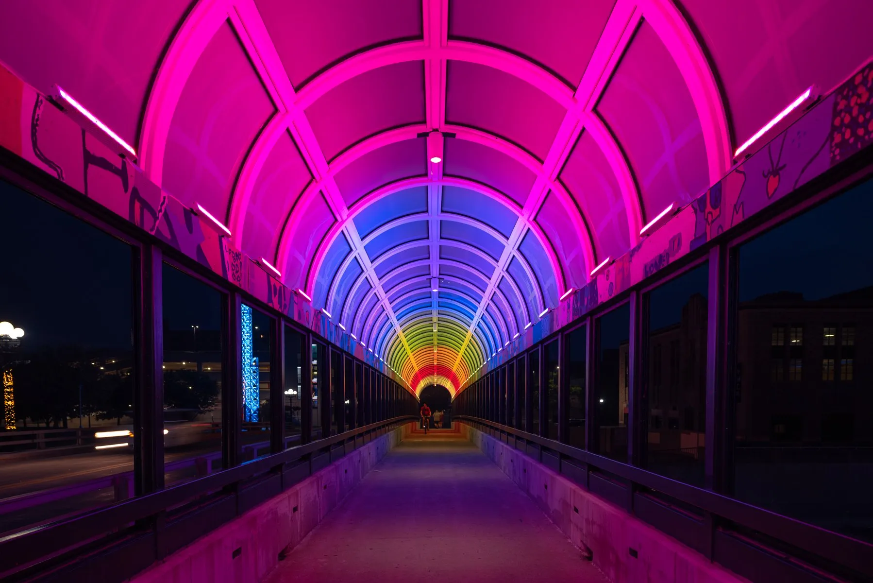 Pedestrian tunnel glowing with magenta and violet LED lighting at night