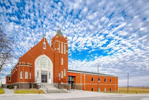 St. Mary-Holy Cross church exterior against a dramatic blue sky, Elkhart, Iowa