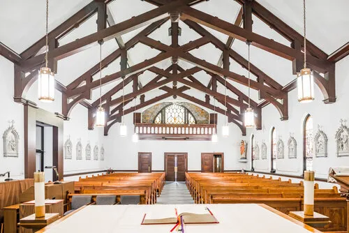 Church interior with white timber trusses and wood pews