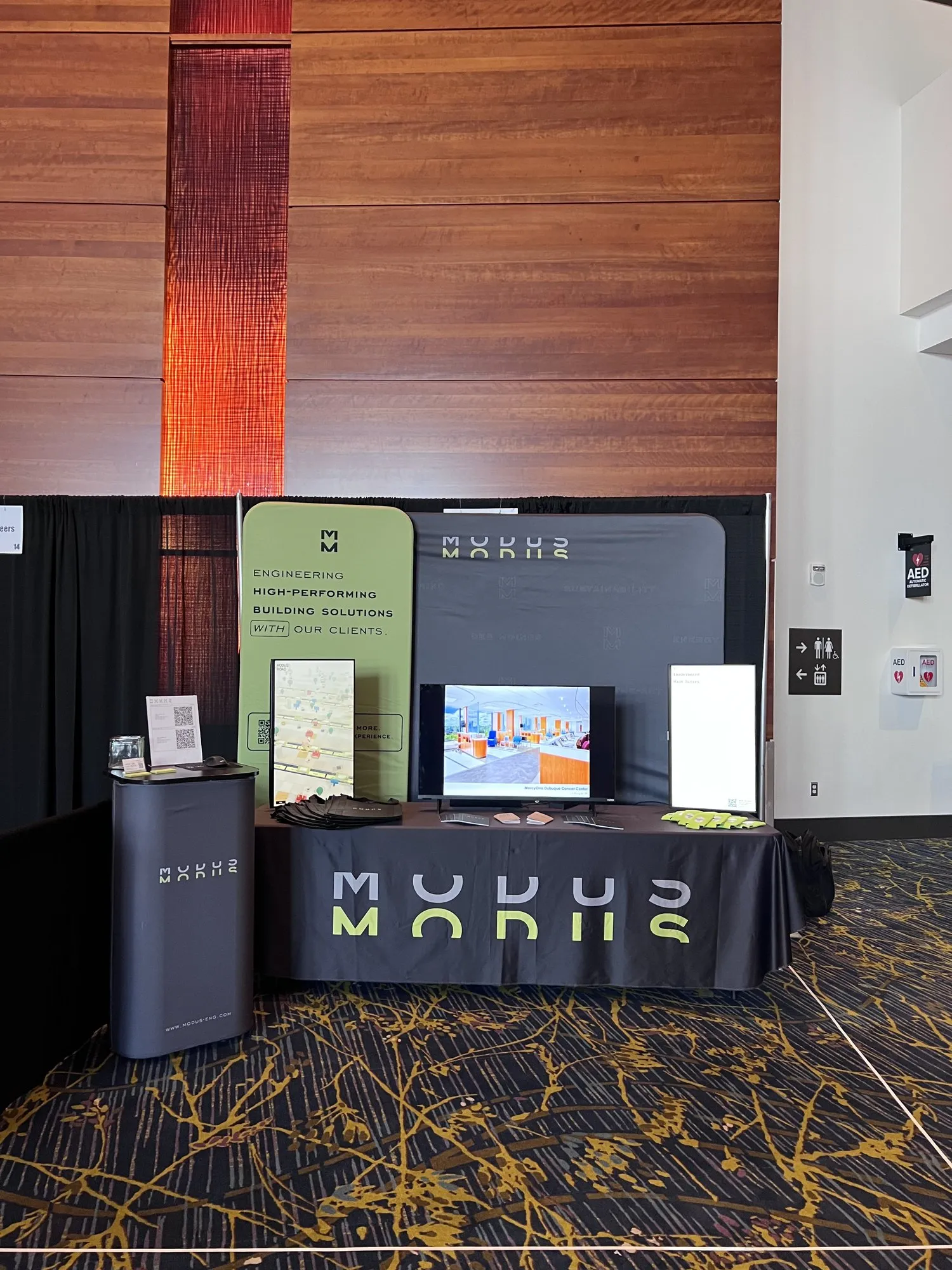 The MODUS booth at AIA Iowa with the MODUS tablecloth, a center screen, display boards and signage