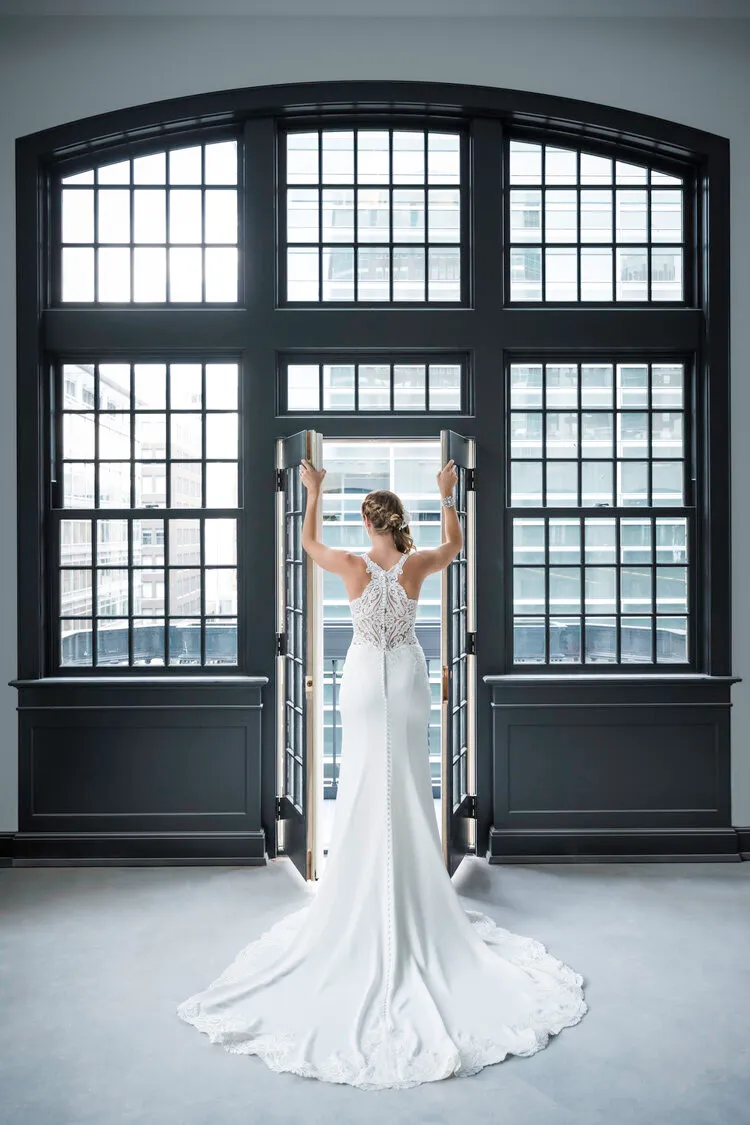 Bride standing before a tall arched window