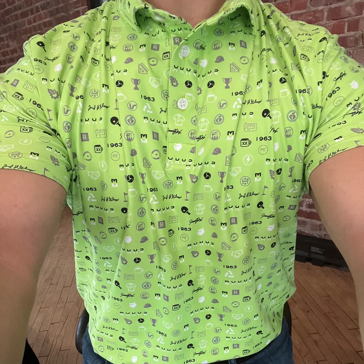 Close-up of the finished lime MODUS culture polo, showing the printed icons