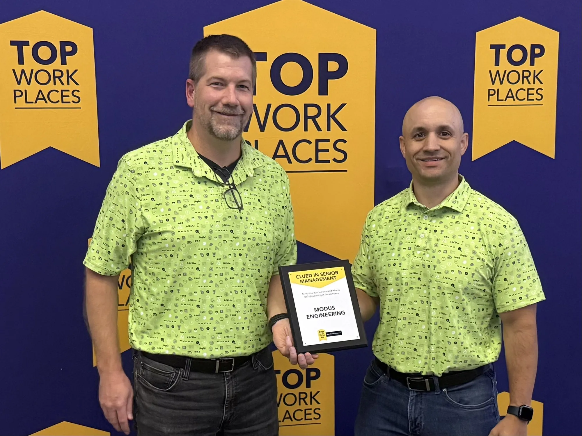 Two MODUS team members wearing the lime culture polo at a Top Workplaces event